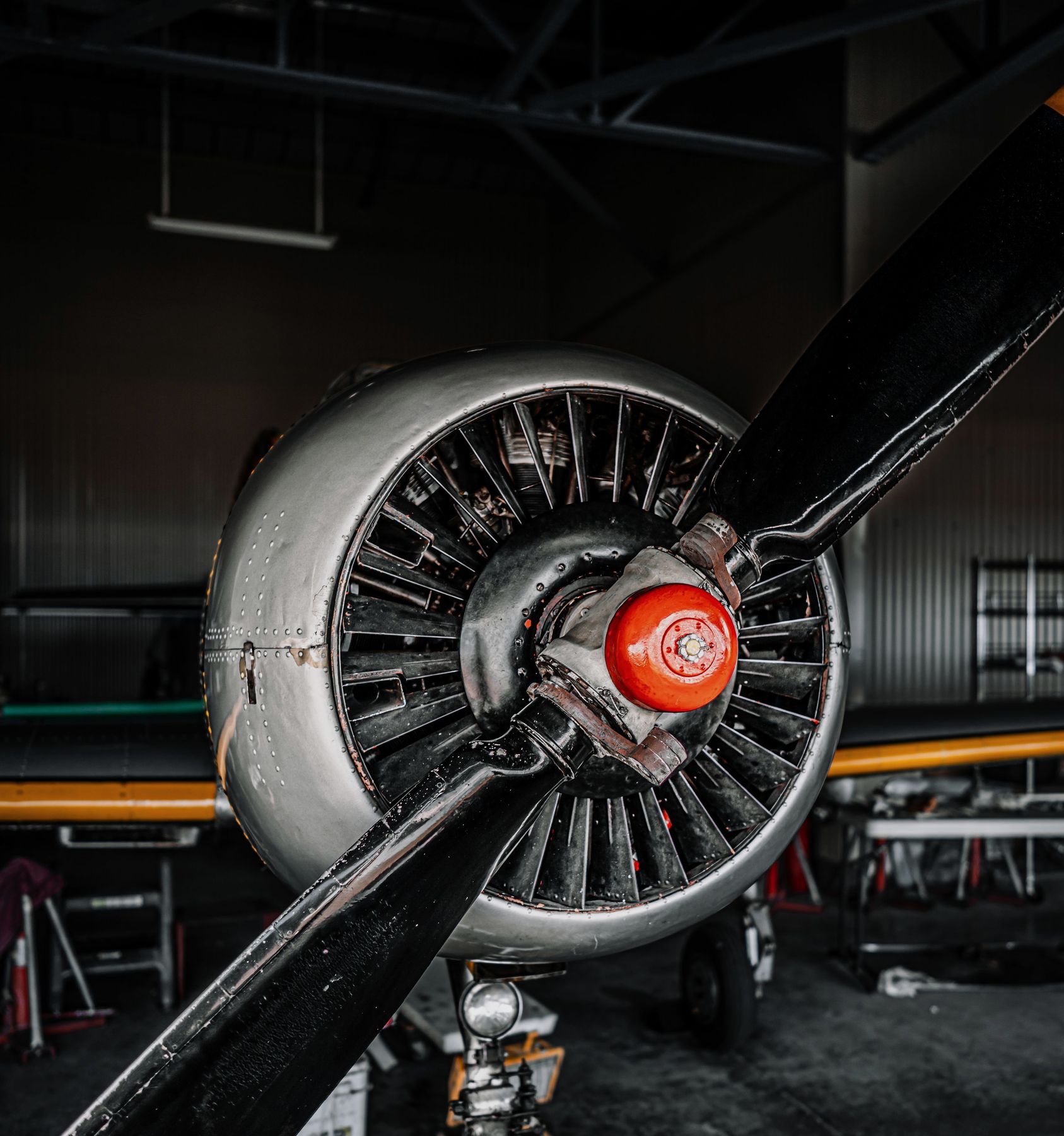 Radial engine and propeller with an orange spinner in a dim hangar